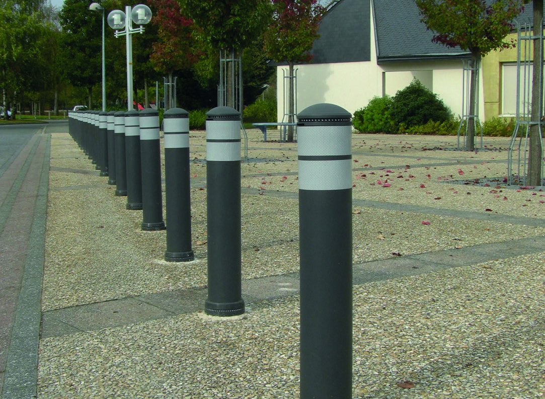 Rij flexibele Jislon-palen met reflecterende banden langs een voetgangersgebied